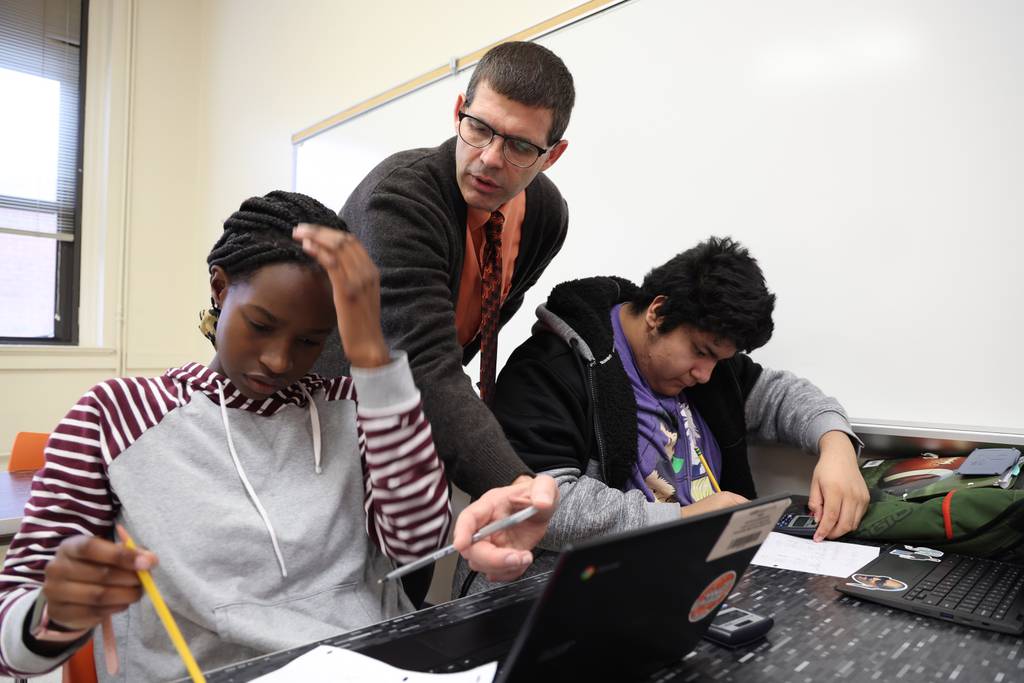 Male teacher supporting two students.